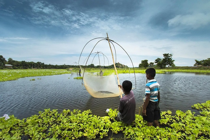 Two young boys fishing with suspended nets in Assam