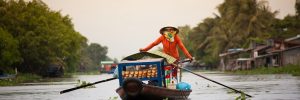 A figure paddling their boat through a Vietnamese floating market on the Mekong