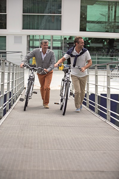A couple wheeling complimentary bicycles back on-board Emerald Liberte after a cycling tour