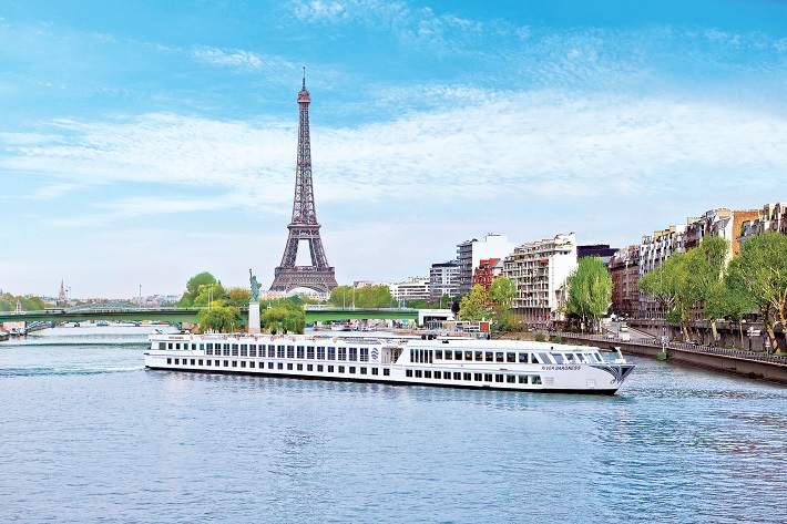A Uniworld river cruise ship sailing down the Seine in Paris, past the Eiffel Tower