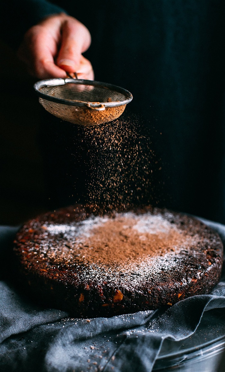 Chocolate being sifted on top of traditional Madeira honey cake